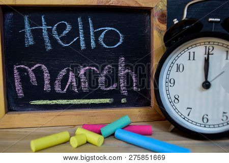 Hello March. Back To School Concept. Alarm Clock On Wooden With Blackboard On Background