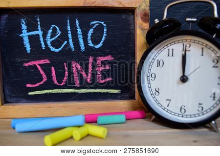 Hello June. Back To School Concept. Alarm Clock On Wooden With Blackboard On Background