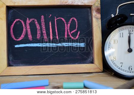 Online. Back To School Concept. Alarm Clock On Wooden With Blackboard On Background