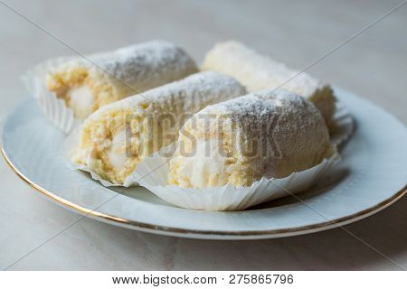 Mini Roll Cake With Vanilla Cream, Coconut And Powdered Sugar.