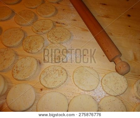Italian Tigelle Ready To Be Cooked On A Knotted Table Near A Rolling Pin