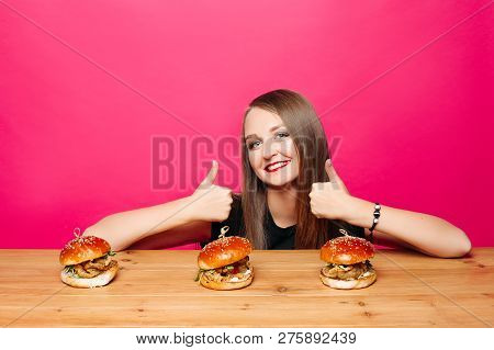 Happy Girl Showing Super By Fingers To Three Humburgers.
