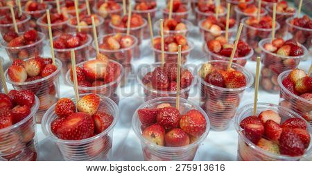 Close-up Fresh Juicy Straweberry In Plastic Disposable Cups With Stick On Stall Of Street Fruit Mark