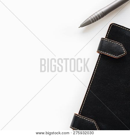 Leather Closed Notebook With Clips With Orange Stitch On Edges Half Seen Put Diagonally And Grey Pen