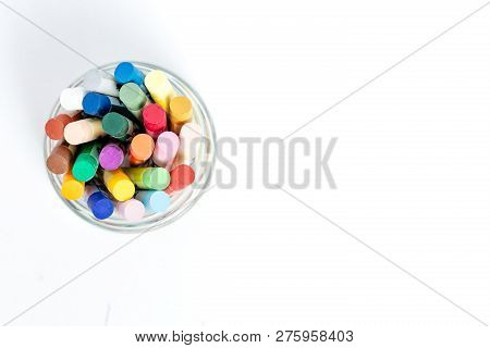 Oil Pestel In A Glass Cup On A White Table.
