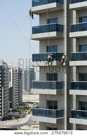 High-rise Workers Wearing Seat Belts Wash The Windows Of A High-rise Building In Dubai