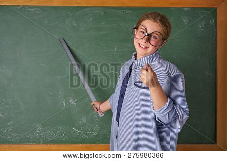 Funny kid girl with teacher costume in green blackboard with school ruller