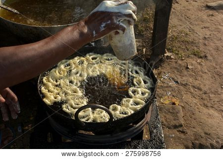 Close Of A Hand Frying Jalebi In Hot Oil In A Street Village Market In A Stove In Daylight
