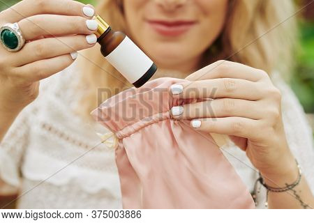 Close-up Image Of Smiling Young Woman Taking Bottle Of Revitalizing Brightening Serum Out Of Light P