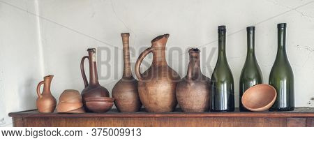 Traditional Georgian Wine Jugs, Clay Cups And Bottles On A Wooden Shelf
