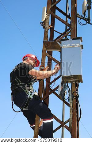 Tehnician In Red Helmet With Multimeter On The Electric Pole