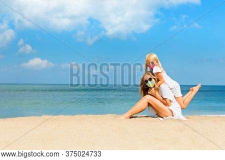 Mother, Child In Masks Have Fun On Sea Beach. New Rules To Wear Cloth Face Covering At Public Places