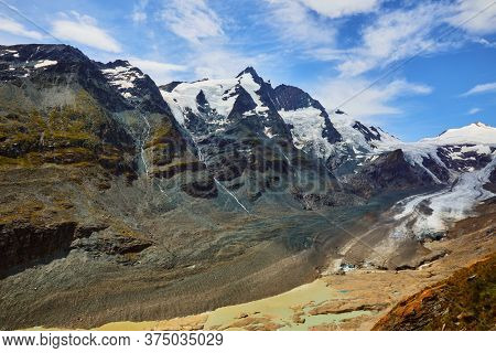 Panoramic view at Pasterze Glacier Grossglockner among austrian Alps mountains summits blue sky clouds.