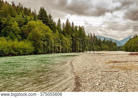 Upper Kitimat, Glacial Green River, On A Cloudy Summer Day, With Rainforests And Gravel Bars, In Bri