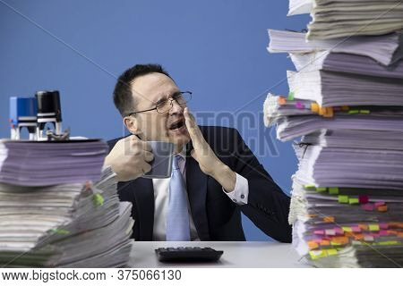 Tired Office Worker Yawns Tired Sitting At Desk With Huge Pile Of Documents. Fatigue And Overload Co