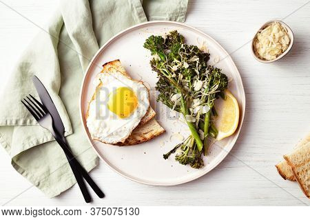 Roasted Broccolini, Lemon, Fried Egg With Tost On The Plate On The Table Decorated With Napkin. Top 