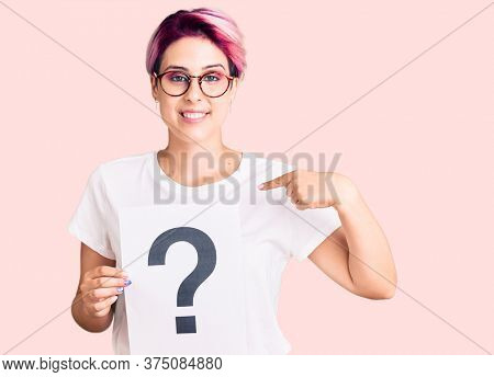 Young beautiful woman with pink hair holding question mark pointing finger to one self smiling happy and proud 