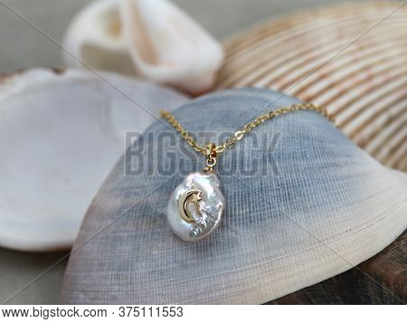 Golden Crescent Moon Baroque Pearl Pendant With Gold Chain On Marine Shell 
Background