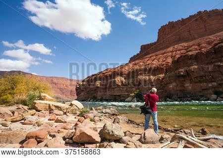 Man tourist with a photo bag photographs a beautiful landscape. USA. Lee's Ferry is a historic boat ferry across the Colorado River. The concept of active and photo tourism