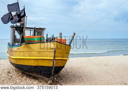 Old And Rusty Fishing Boat And Equipment On Sandy Beach, Getting Ready For Fishing Trip. Blue Sea In