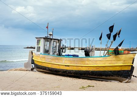Old And Rusty Fishing Boat And Equipment On Sandy Beach, Getting Ready For Fishing Trip. Pier And Bl