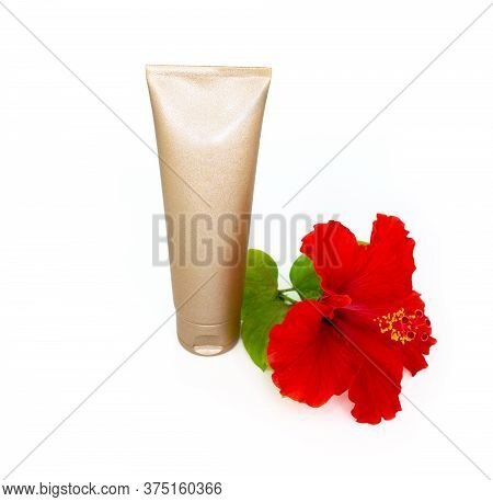 Golden Cream Bottle And Tropical Flower On The White Background.