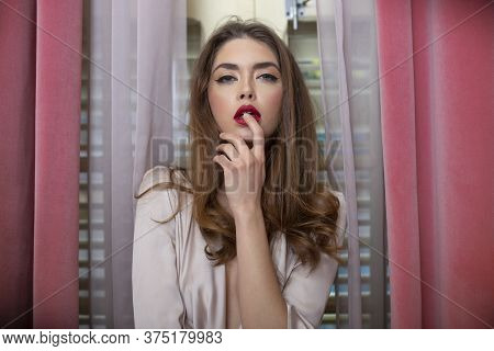 Frontal Portrait Of A Sexy Woman With Long Waving Hair And Makeup Posing In Silk Pink Dress Near Win