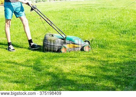 Young Man Mows The Lawn. High Quality Photo