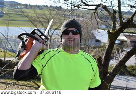 Worker In The Garden With A Chainsaw. Concept: Spring Garden Work.