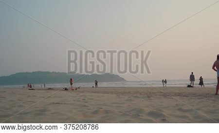Morjim, India December 14, 2019: People Walk On The Beach At Sunset. The Concept Of A Lane Along The