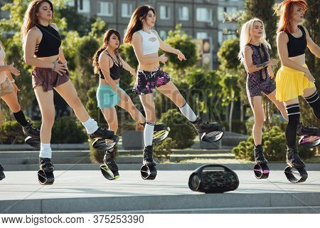 Beautiful Women In Sportswear Jumping In A Kangoo Jumps Shoes At The Street On Summers Sunny Day. Ju