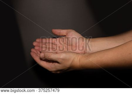 The Man Whose Hand Is Praying On The Dark Background,selective Focus.