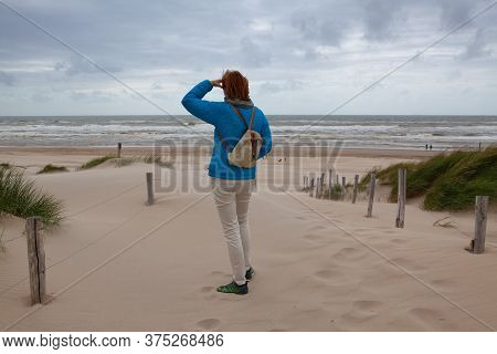 Petten, Netherlands - June 29,2020: A Lonely Tourist Looks Out For A Better Tomorrow On A Beach Cove