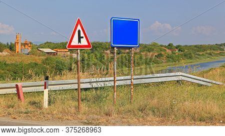 Two Traffic Signs At Road Side Near Water Canal
