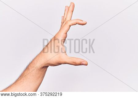 Close up of hand of young caucasian man over isolated background picking and taking invisible thing, holding object with fingers showing space 