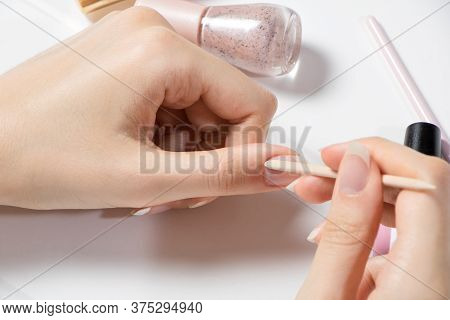 Manicure. Push Back The Cuticle With A Wooden Stick. A Woman Does Her Own Manicure. Home Nail Care. 