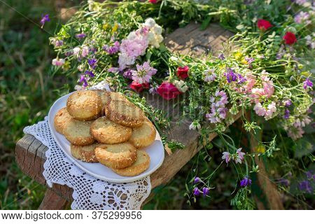 Shortbread Cookies With Blue Cheese And Sesame Seeds And A Wreath Of Wildflowers On A Wooden Bench. 