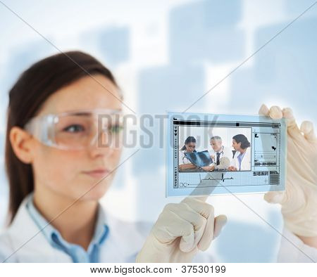 ผู้หญิงชี้บนรูปภาพของแพทย์และพยาบาล loking ที่ x ray บนอินเทอร์เฟซโฮโลแกรมบนสีน้ำเงินและ whi