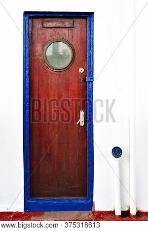 Old Wooden Dusty  Door In A Blue Fraim On A Steamboat On A White Wall