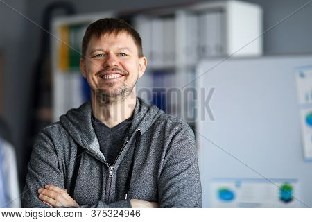 Self-satisfied Man Is Standing In Room And Smiling. An Unshaven Man Is Standing At Home And Smiling.