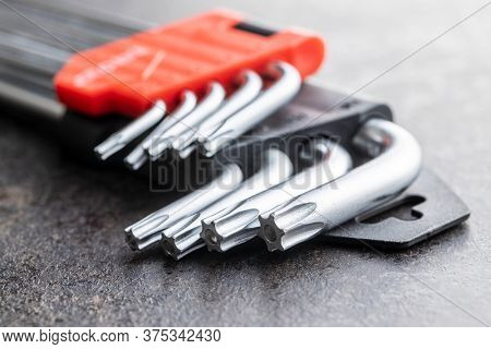 Metal torx screwdrivers on black table.