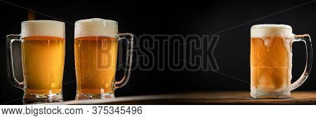 Three Cold Mugs With Beer, With Overflowing Foam, On Wooden Table And Dark Background, Space For Wri