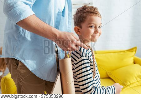 Cropped View Of Man Fixing Carton Plane Wings On Back Of Happy