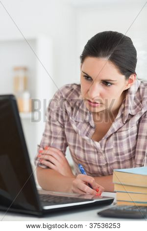 Kvinden skriver på en notebook mens du kigger på laptop i lving værelse