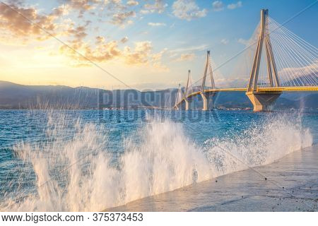 Amazing view - Modern Bridge at the evening sunset time with waves splash. Rion-Antirion Bridge, Greece, Europe. The Rion-Antirion Bridge in Greece one of the world's longest  bridge