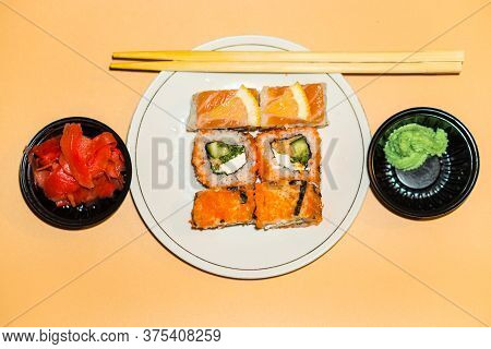 Sushi Rolls Lie In A White Plate On An Orange Background