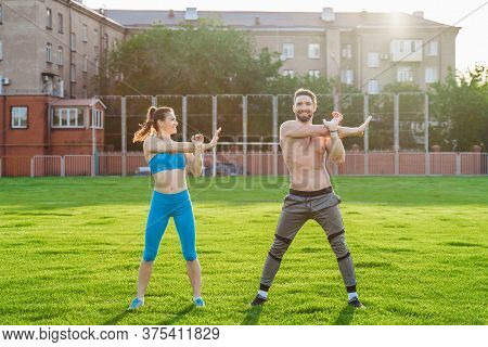 Attractive Young Couple Man And Woman 25 Years Old Are Doing Exercises On A Sunny Summer Morning On