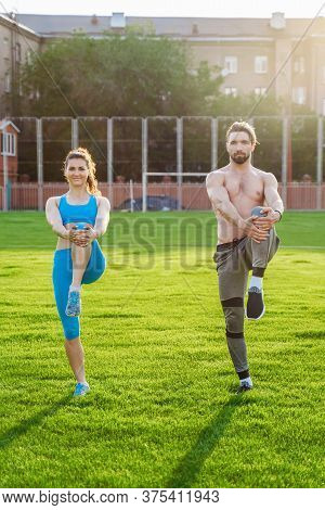 Attractive Young Couple Man And Woman 25 Years Old Are Doing Exercises On A Sunny Summer Morning On