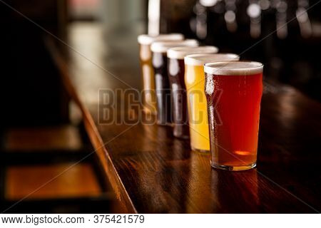 Fun, Company And Oktoberfest. Lager, Ale And Light, Dark And Unfiltered Beer In Glasses On Wooden Ba