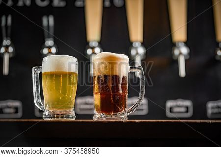 Two Mugs Full Of Chopp, One With Pilsen Chopp And One With Dark Chop On A Rustic Table